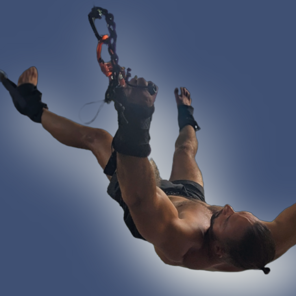 Low-angle view of a man during a Pravilo session, highlighting the suspension cuffs and the full extension of the body.